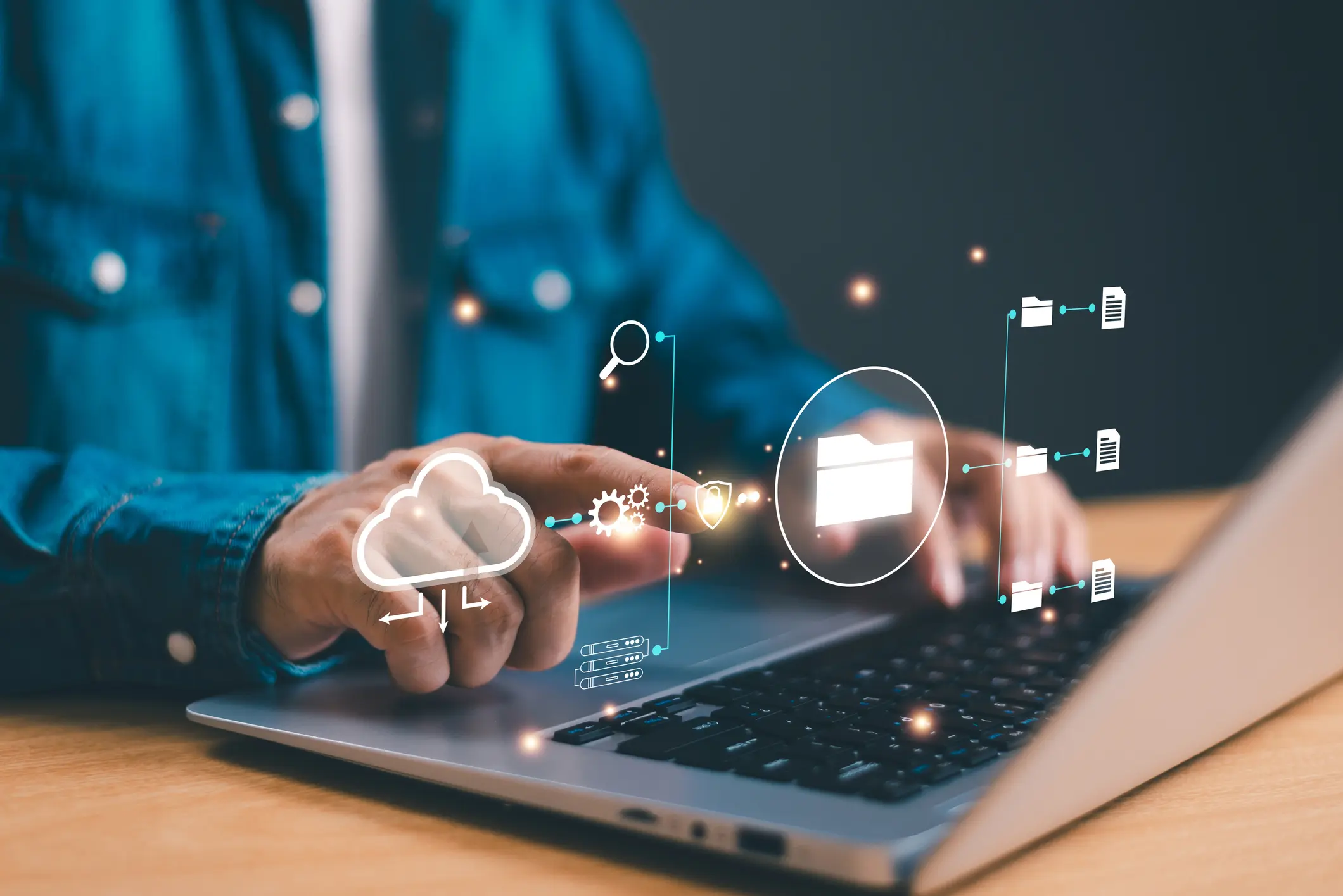 Hands typing on laptop with cloud icons