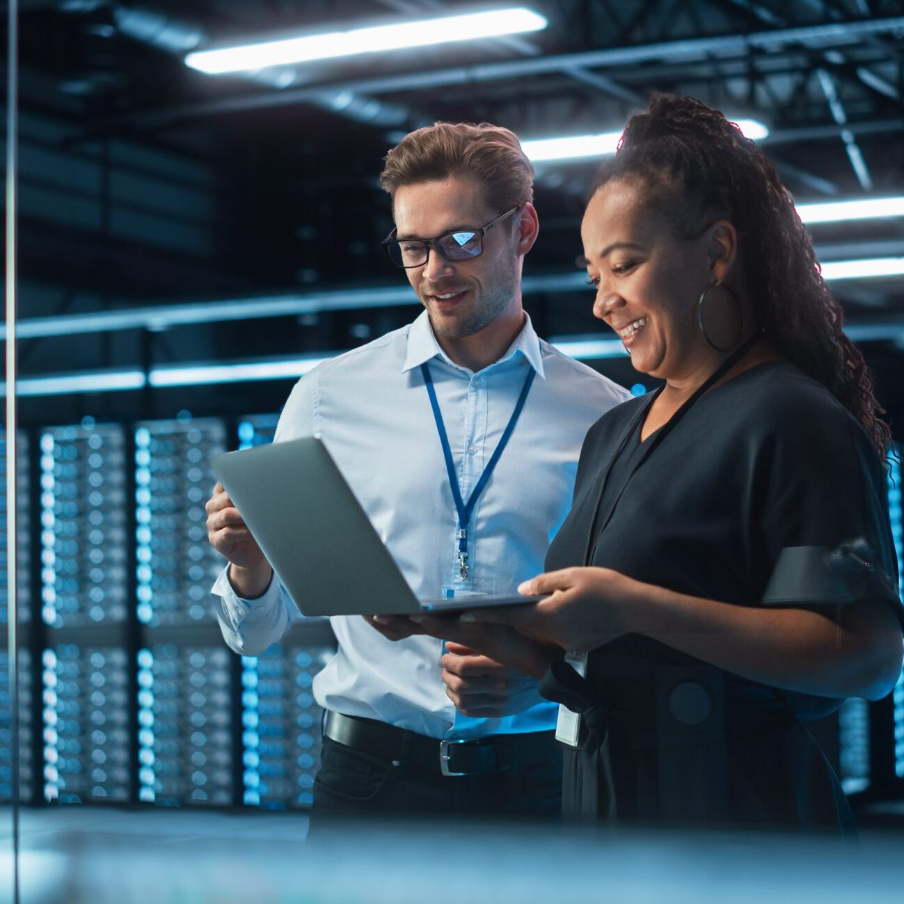 Two IT professionals reviewing laptop in server room